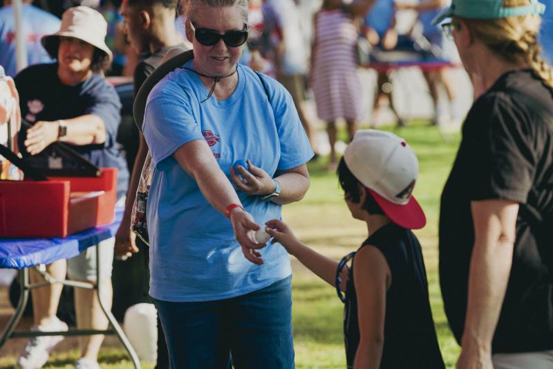 Volunteer helping child at carnival game at Willmeng Arizona Celebration of Freedom